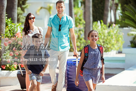 Family with suitcases walking towards tourist resort