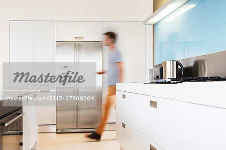 Man walking towards refrigerator in his modern kitchen