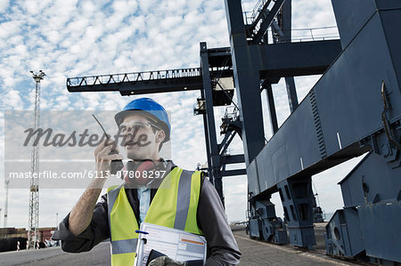 Worker using walkie-talkie near crane Worker using walkie-talkie near crane