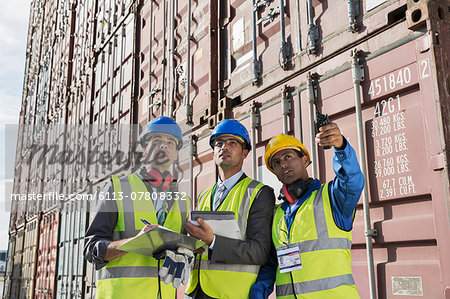 Businessmen and worker talking near cargo containers