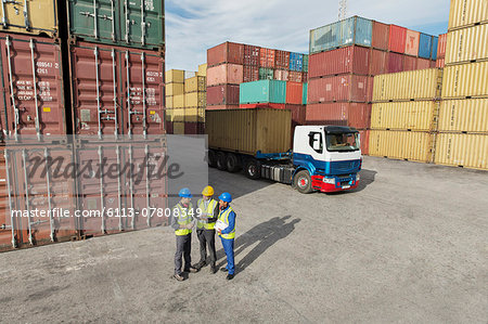 Businessmen and worker talking near cargo containers