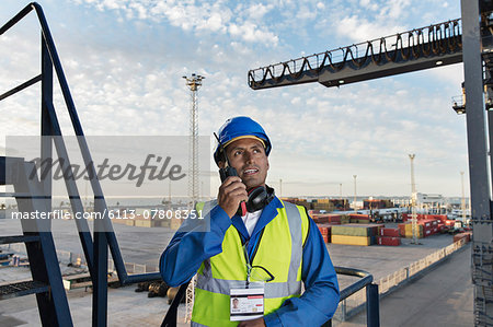 Worker using walkie-talkie on cargo crane
