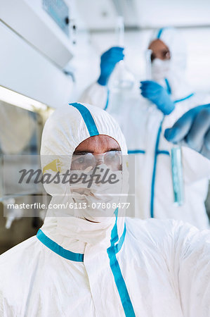 Scientist in clean suit examining test tube in laboratory