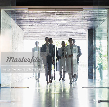 Scientists and business people approaching glass doors