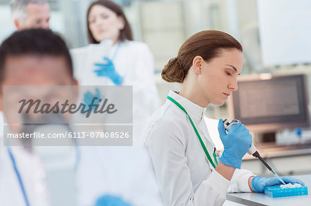 Scientist pipetting sample into tray in laboratory