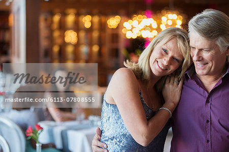 Man embracing woman in restaurant, people in background