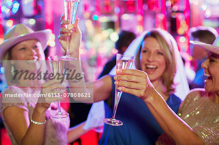 Women toasting with champagne flutes at bachelorette party Women toasting with champagne flutes at bachelorette party