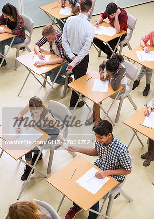 Overhead view of students passing note between desks during their GCSE exam