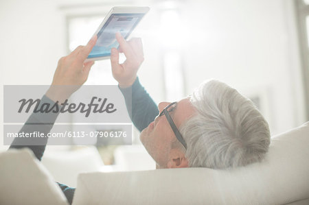 Older man using digital tablet in living room