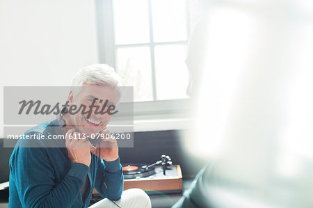 Older man listening to turntable with headphones