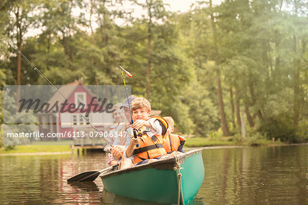 Father and sons fishing from canoe in lake