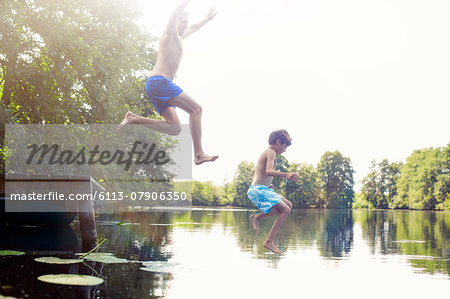 Father and son jumping into lake