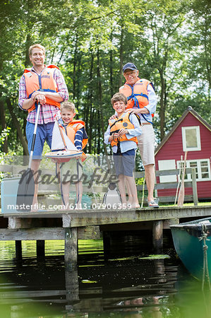 Brothers, father and grandfather wearing life jackets at lake
