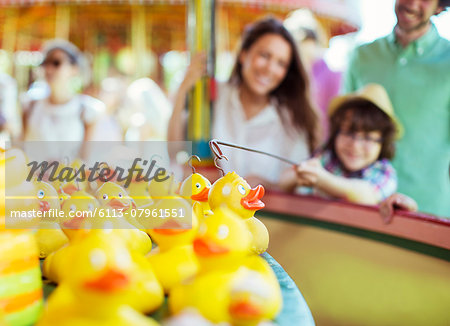 Boy trying to catch rubber duck on fishing game in amusement park