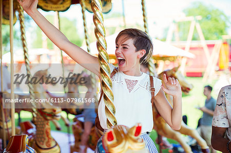 Cheerful woman sitting on horse on carousel in amusement park
