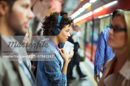 Woman listening to headphones in train station
