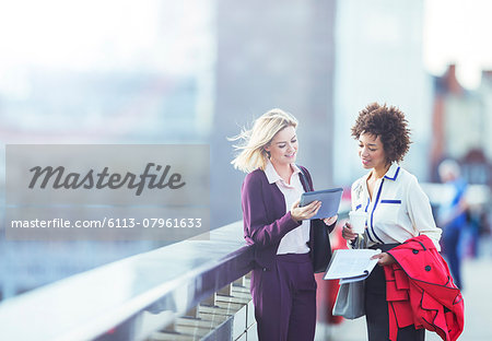 Businesswomen using digital tablet on urban bridge Businesswomen using digital tablet on urban bridge