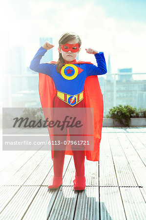 Superhero girl flexing muscles on city rooftop