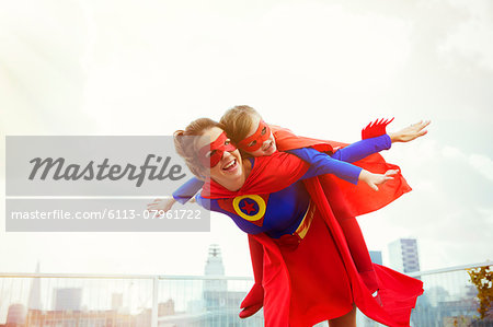 Superhero mother and daughter playing on city rooftop