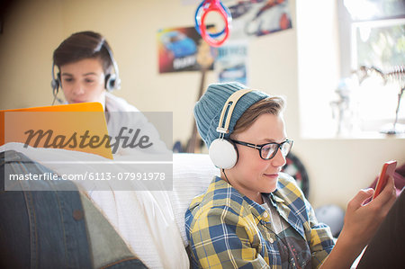 Two teenage boys using electronic devices in room