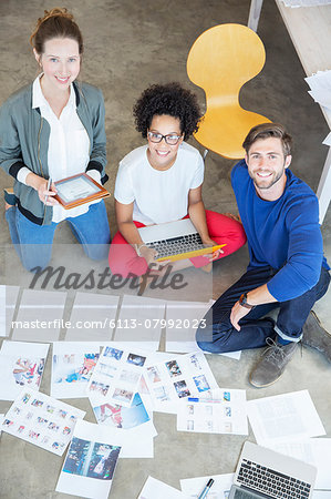 Portrait of three young people sitting on floor and working together