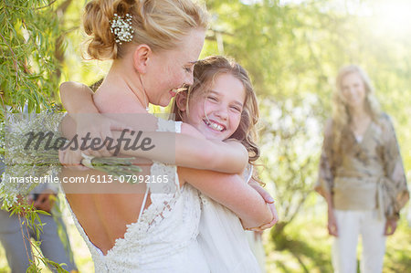 Bride embracing bridesmaid at wedding reception in domestic garden