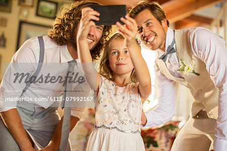 Bridegroom, best man and bridesmaid photographing self in domestic room