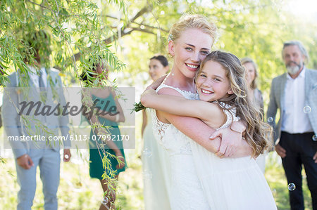 Bride embracing bridesmaid at wedding reception in domestic garden