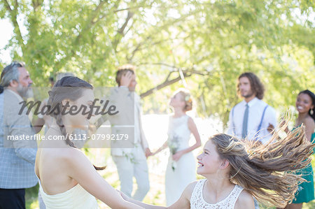 Bridesmaid and girl dancing during wedding reception in domestic garden