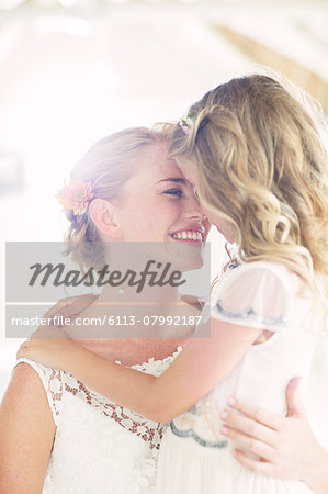 Bride holding bridesmaid in domestic room