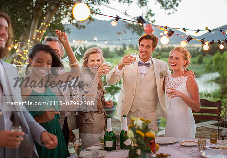 Young couple and guests toasting with champagne during wedding reception in domestic garden