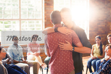 Men hugging at group therapy session