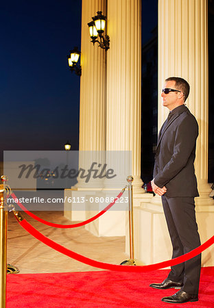 Serious Bodyguard Standing with Sunglasses and Security Earpiece