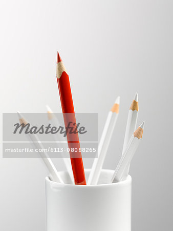 Tall red pencil in cup with smaller white pencils still life