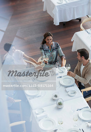 Friends toasting wine glasses at restaurant table