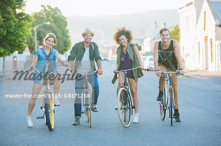 Portrait smiling friends sitting on bicycles on road