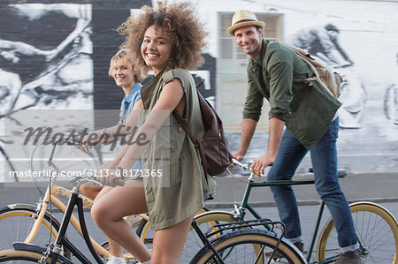 Portrait smiling friends riding bicycles on urban street