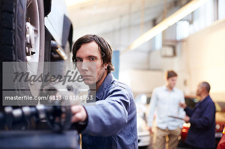 Mechanic reaching for part in auto repair shop