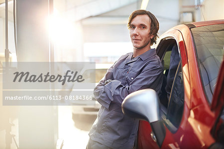 Portrait confident mechanic leaning on car in auto repair shop