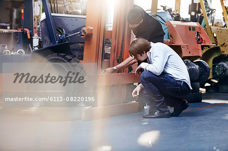 Mechanic and customer examining forklift in auto repair shop