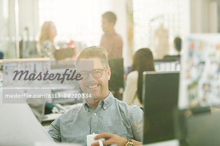 Portrait smiling fashion designer drinking coffee in office