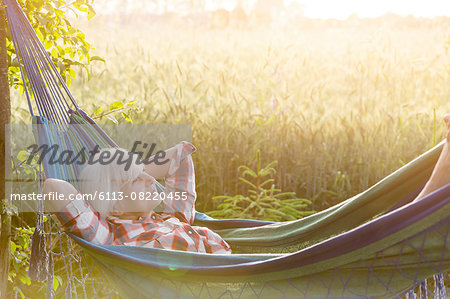 Serene senior woman laying in hammock next to rural wheat field