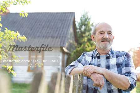 Confident farmer leaning on fence outside farmhouse Confident farmer leaning on fence outside farmhouse