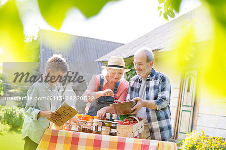 Grandparents and grandson selling honey at farmer's market stall