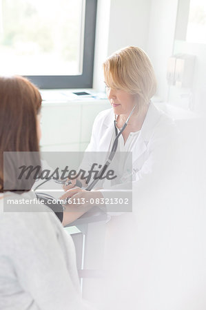 Doctor checking patient's blood pressure in examination room