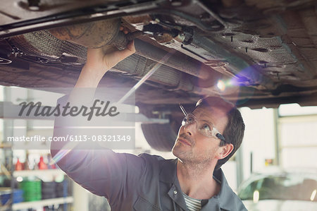 Mechanic working under car in auto repair shop