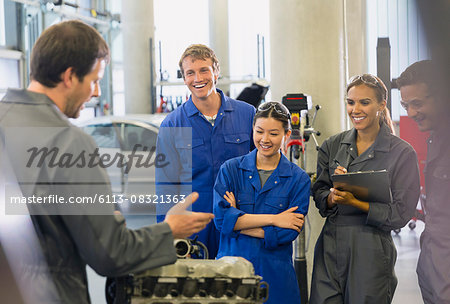 Mechanics discussing car engine in auto repair shop