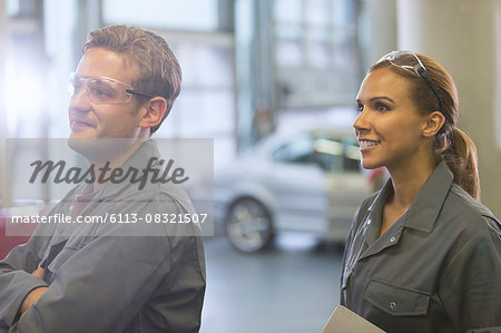 Smiling mechanics looking away in auto repair shop
