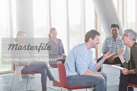 Business people talking and laughing face to face in meeting