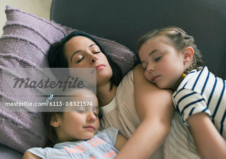 Serene mother and daughters napping on sofa